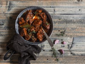 Braised beef in a frying pan on a wooden table