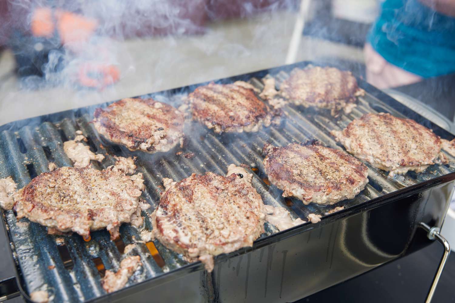 Burger patties cooking on a Weber Go-Anywhere Charcoal Grill