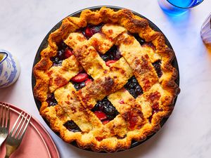 Buttery pie crust with berries and lattice work baked and served with plates and forks