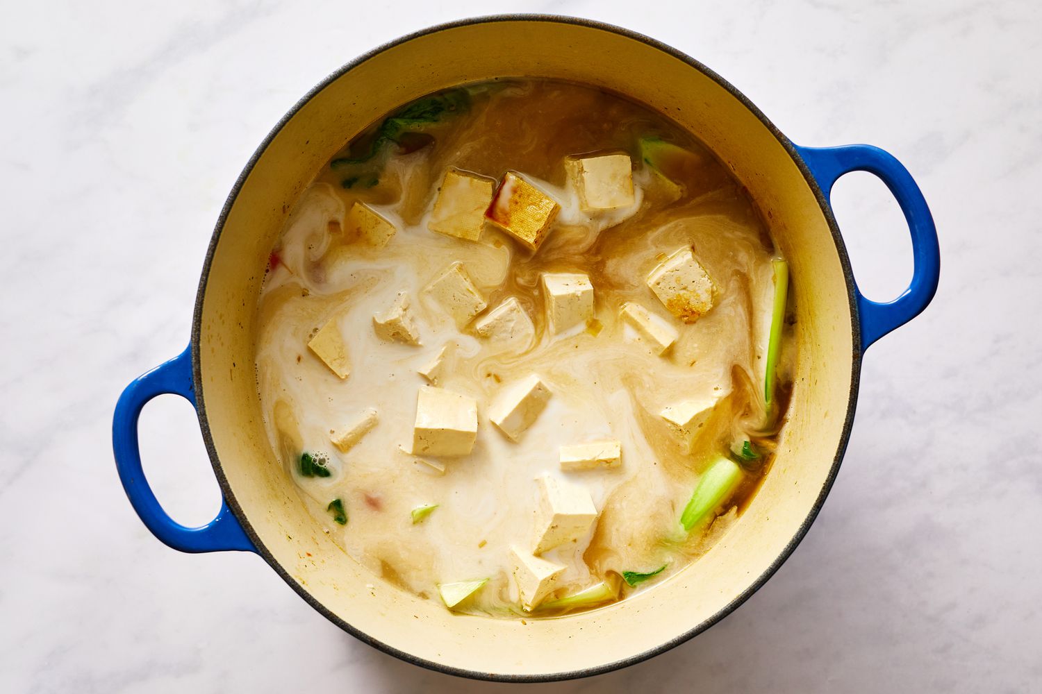 Coconut milk and tofu added to soup pot