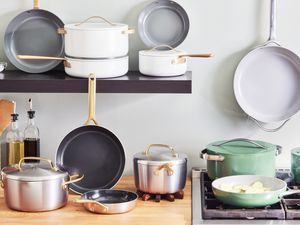 Ceramic cookware sets we recommend displayed in a kitchen on a butcher block countertop, black shelf, and a stovetop