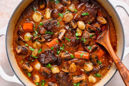 A large pot of beef bourguignon topped with chopped parsley 