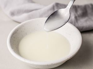 Lemon glaze on a spoon over a white bowl