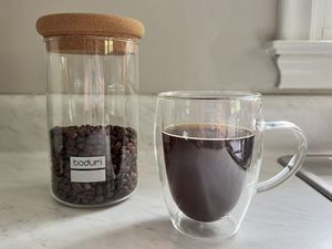 Bodum Yohki Storage Jar with Cork Lid next to a transparent mug full of coffee