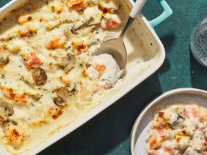 A seafood casserole with a small plated portion and a glass of sparkling water