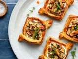 A plate with four mushroom and ricotta puff pastry tarts, with a small bowl of coarse salt