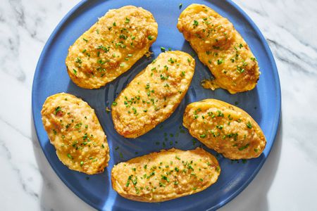 A blue plate with French onion twice baked potatoes, garnished with chives