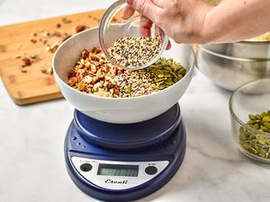 Adding spices to a bowl of dry nuts on the Escali Primo kitchen scale