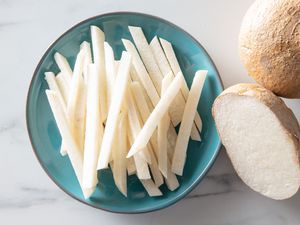 A small plate of matchstick-cut jicama, with a half and whole jicama in frame