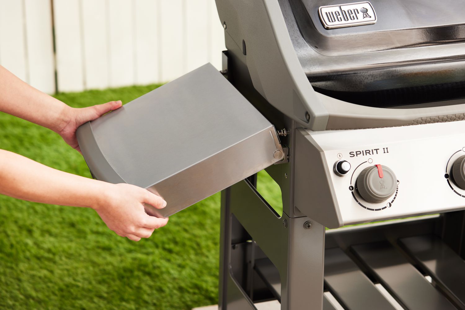 Hands attaching the side table to the Weber Spirit II E-310 3-Burner Gas Grill