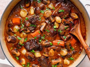 A large pot of beef bourguignon topped with chopped parsley 