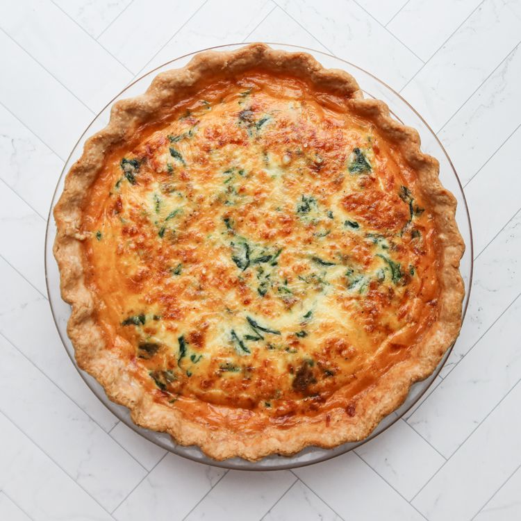 A golden brown quiche with a fluted pastry crust