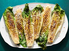 Grilled romain lettuces garnished with parmesan on a white platter. 