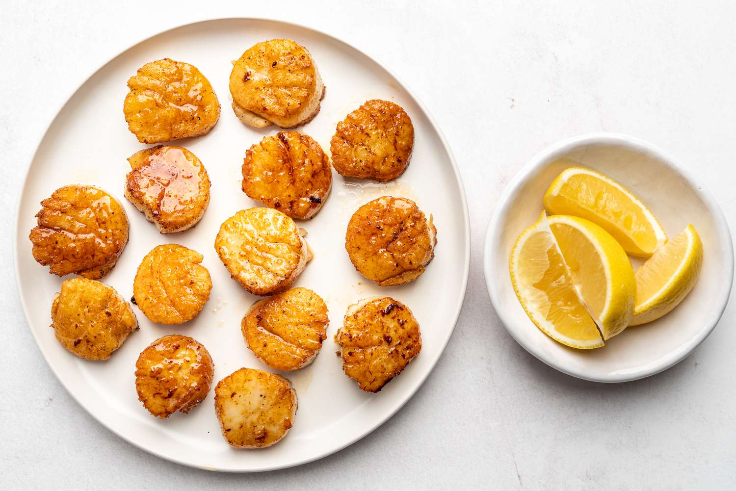 Spicy Seared Scallops on a plate, lemon wedges in a bowl 