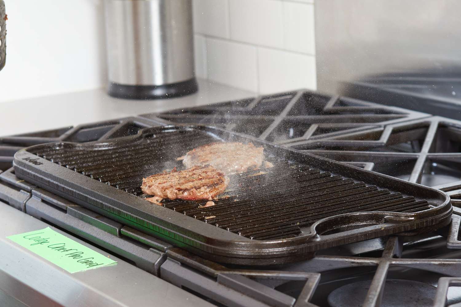 Two burger patties being cooked on the grill side of the Lodge Cast Iron Reversible Grill/Griddle.