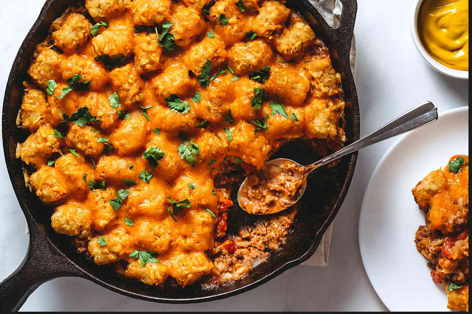 Cheeseburger Casserole in a cast iron pan with a spoon 