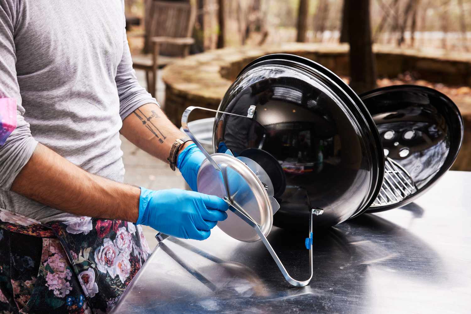 Person assembling a Weber Smokey Joe Charcoal Grill on a table outside 