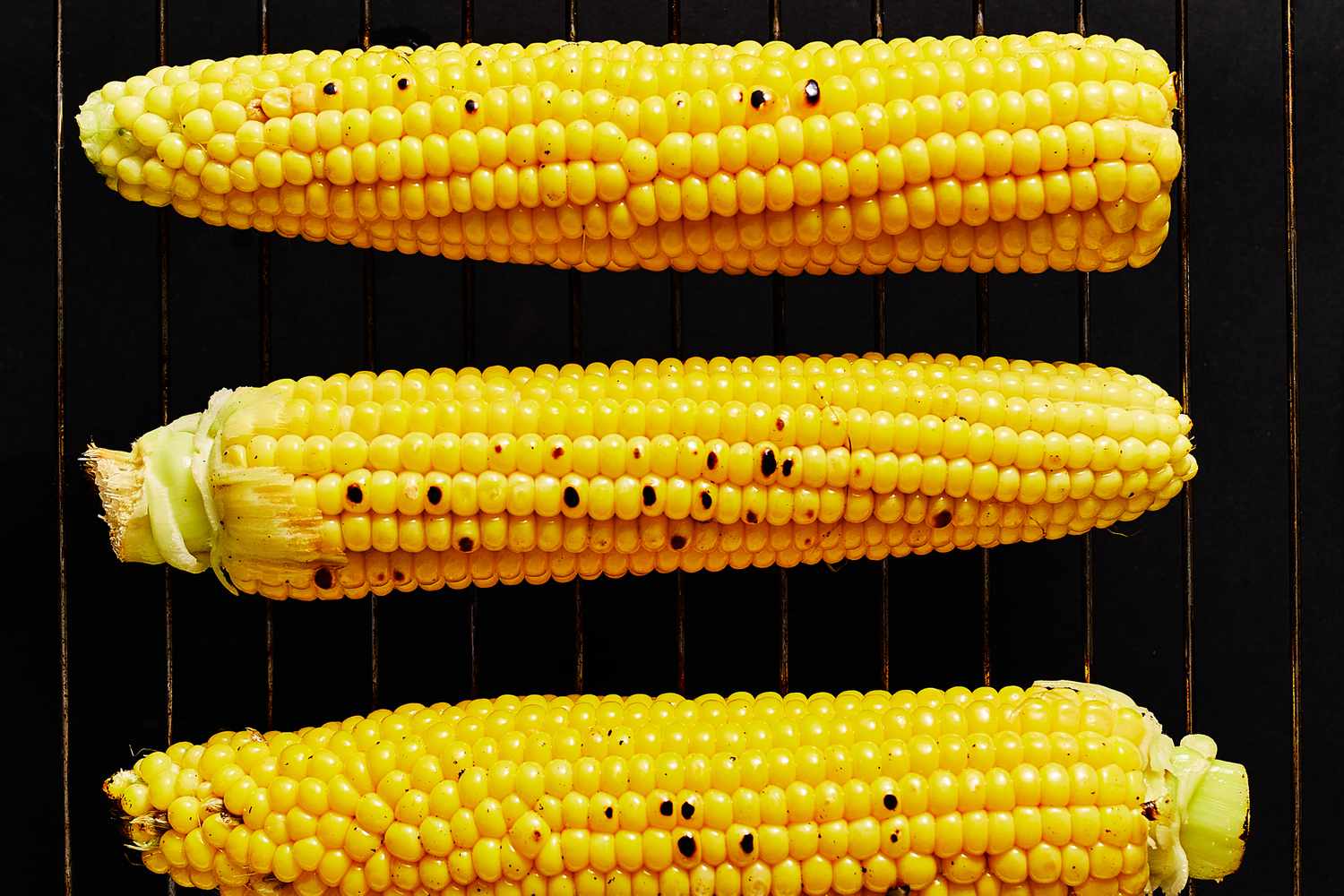 Ears of corn cooking on a grill