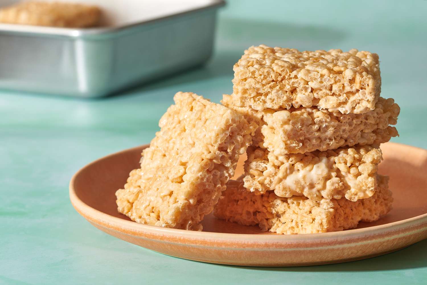 A plate of rice crispy treats with a pan of rice crispy treats in the background