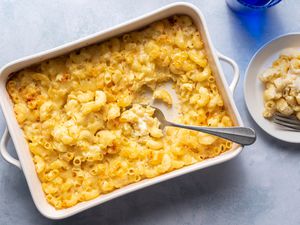 A baked macaroni and cheese casserole with a serving spoon and a plate