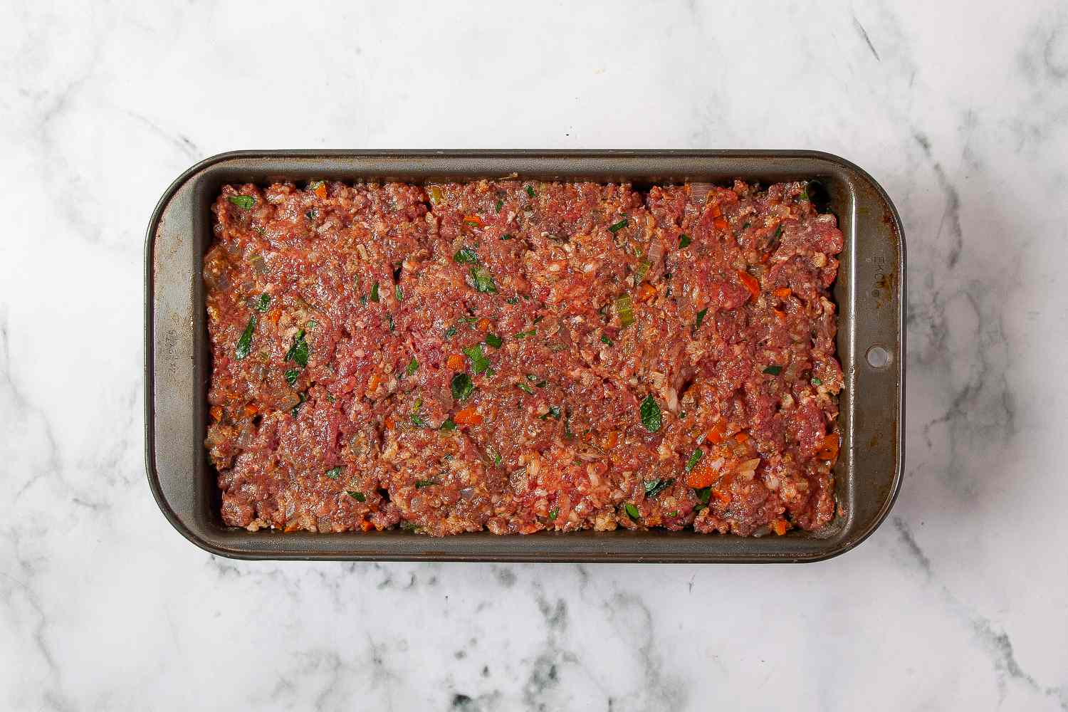 Meatloaf mixture evenly filling a loaf pan