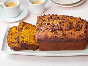 A loaf of sliced pumpkin bread served with coffee