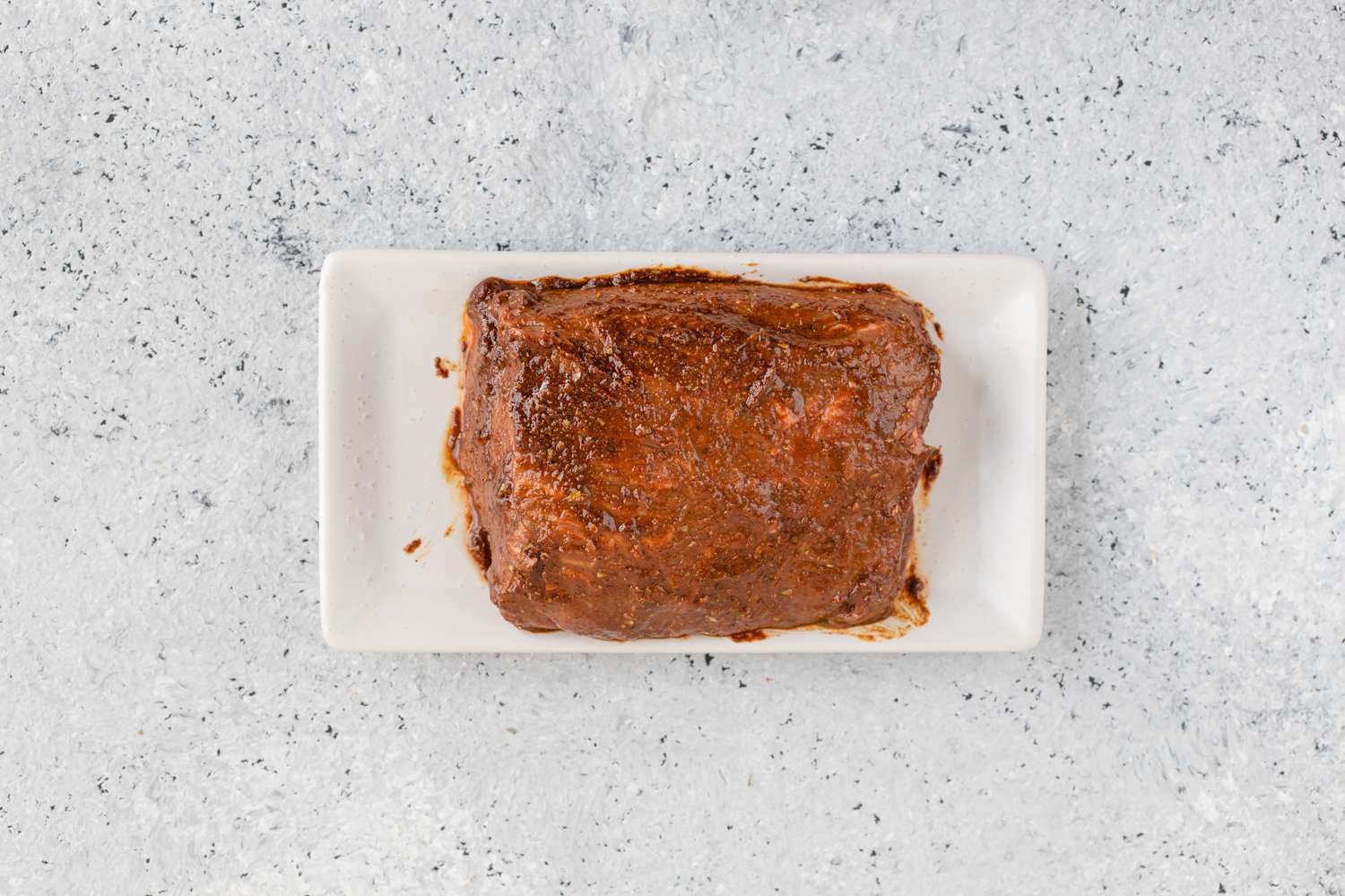 Tri-tip roast rubbed with spice mixture in a rectangular baking dish