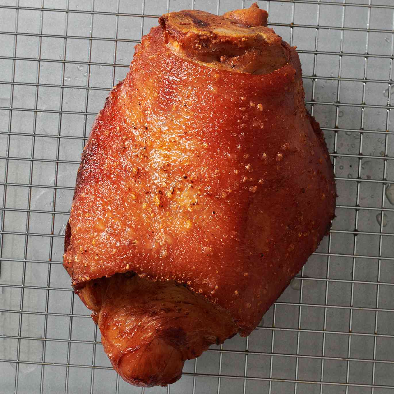 A golden brown fried ham hock on a wire rack