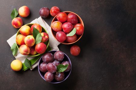 Three bowls of stone fruit: plums, nectarines, and peaches