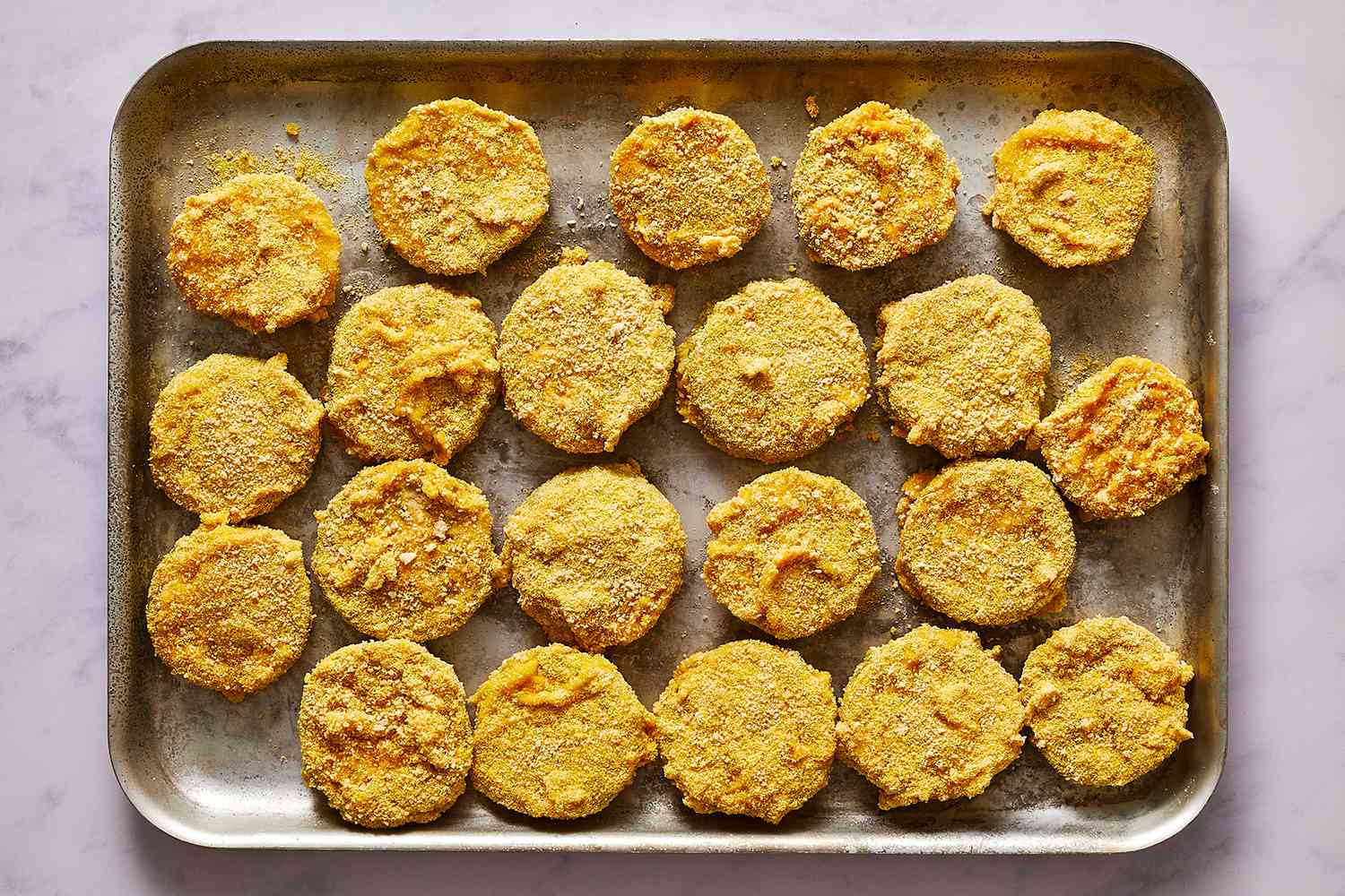 breaded green tomatoes on a baking sheet