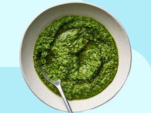 A bowl of bright green pesto with a spoon in it