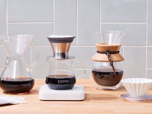Four pour over coffee makers displayed on a wooden counter
