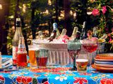 An outdoor table with a selection of wines, glasses, and cups