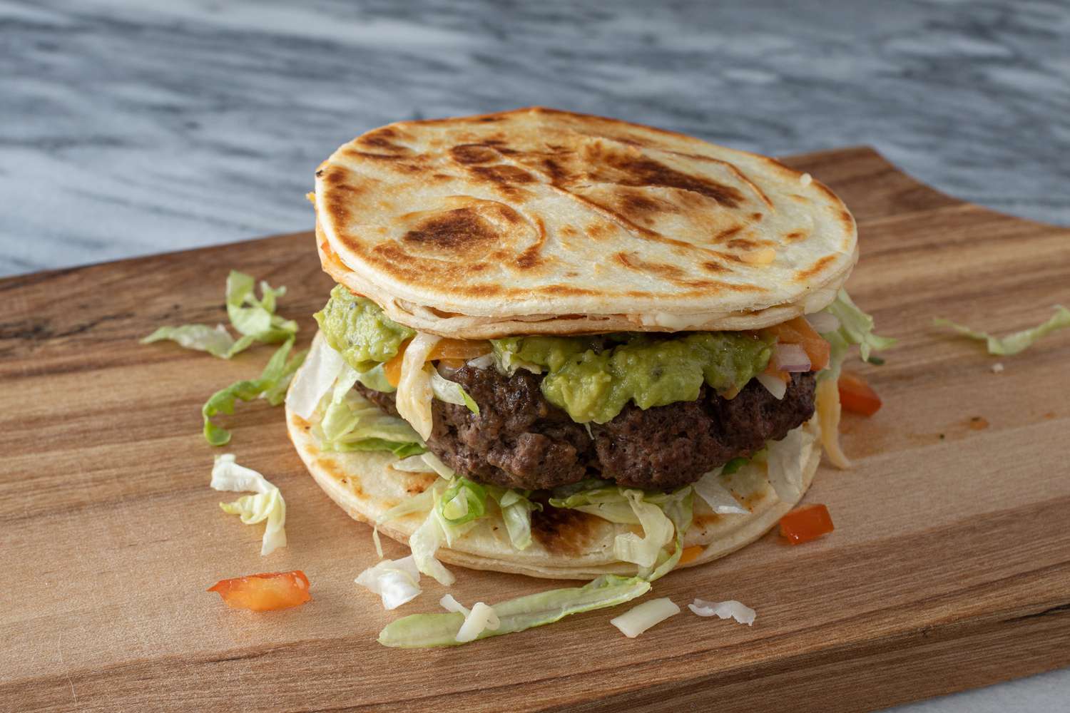 Quesadilla burger assembled on cutting board.