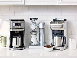 Several coffee makers with grinders displayed on a kitchen counter
