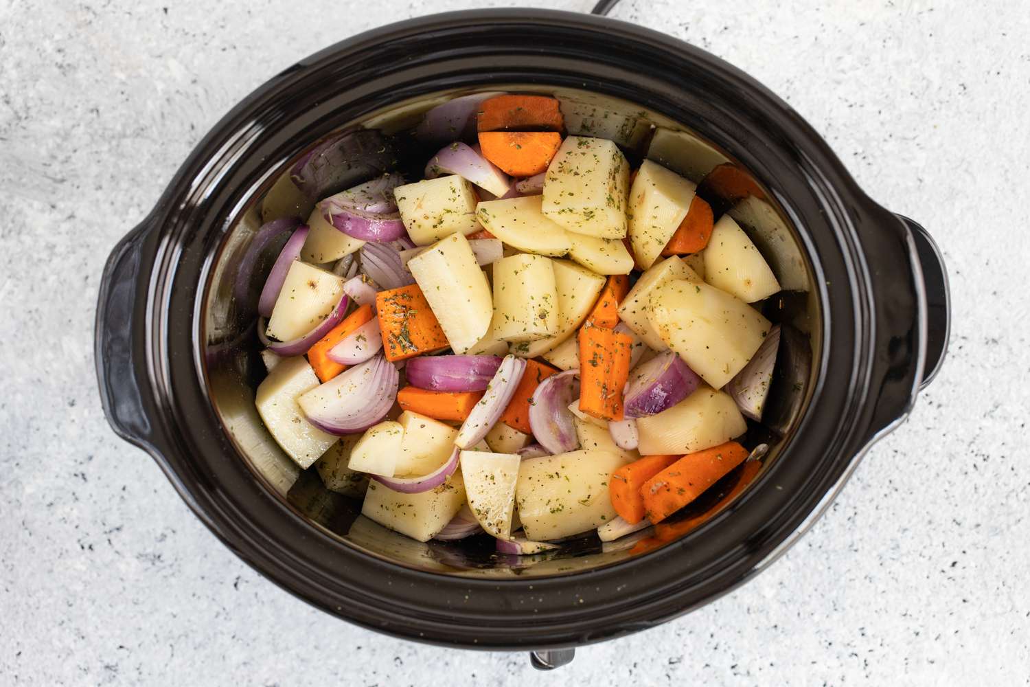 Vegetable chunks tossed in oil in the slow cooker