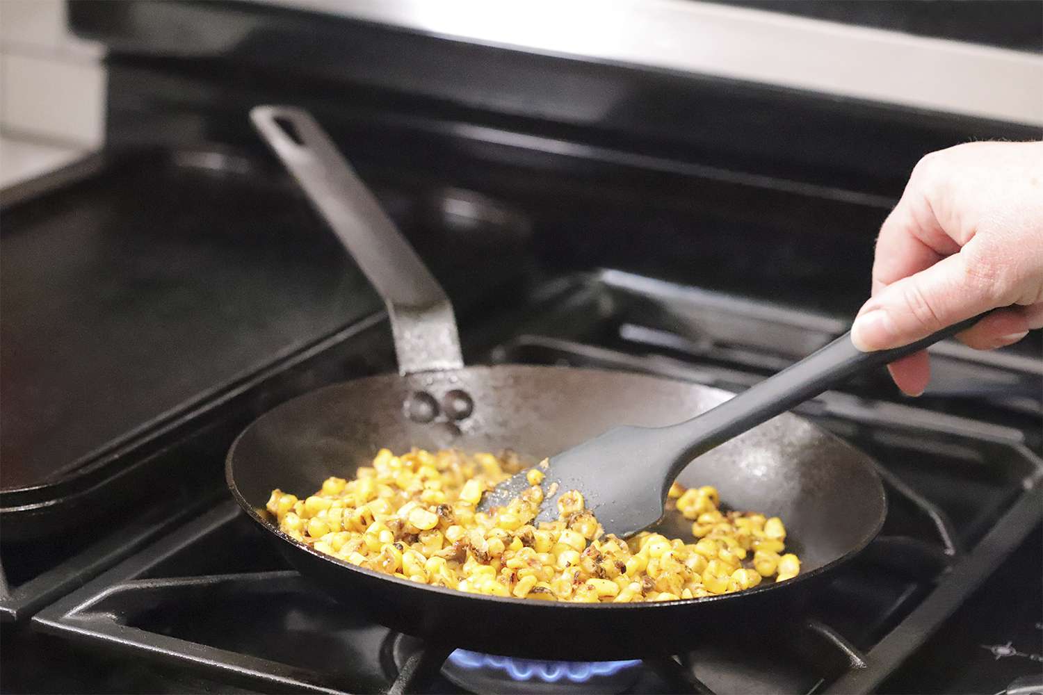 Hand mixing food on the Lodge Seasoned Carbon Steel Skillet on a stove