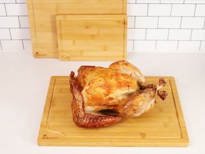 Cooked whole chicken resting on a Kikoin wooden cutting board