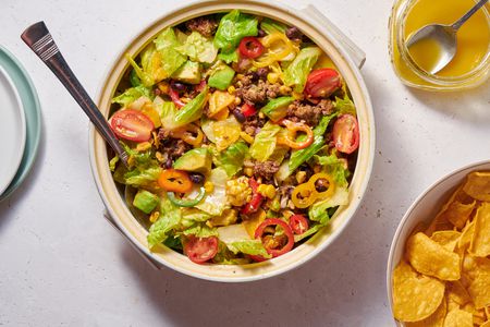 A taco salad served with tortilla chips and extra dressing