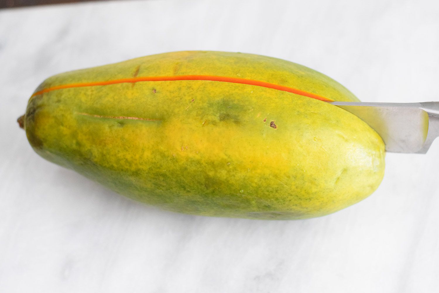 papaya being cut in half with knife