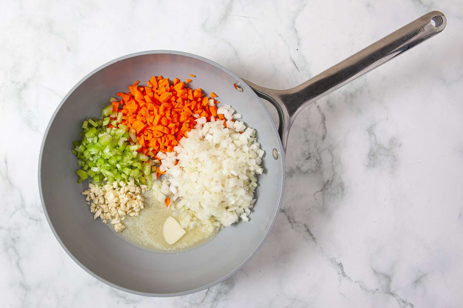 Onion, carrot, celery, and garlic with melted butter in a frying pan