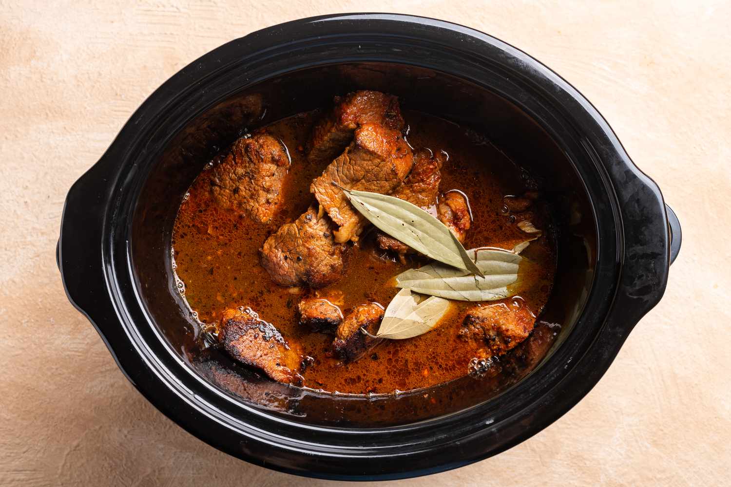 bay leaves and stock mixture added to the beef in the slow cooker 