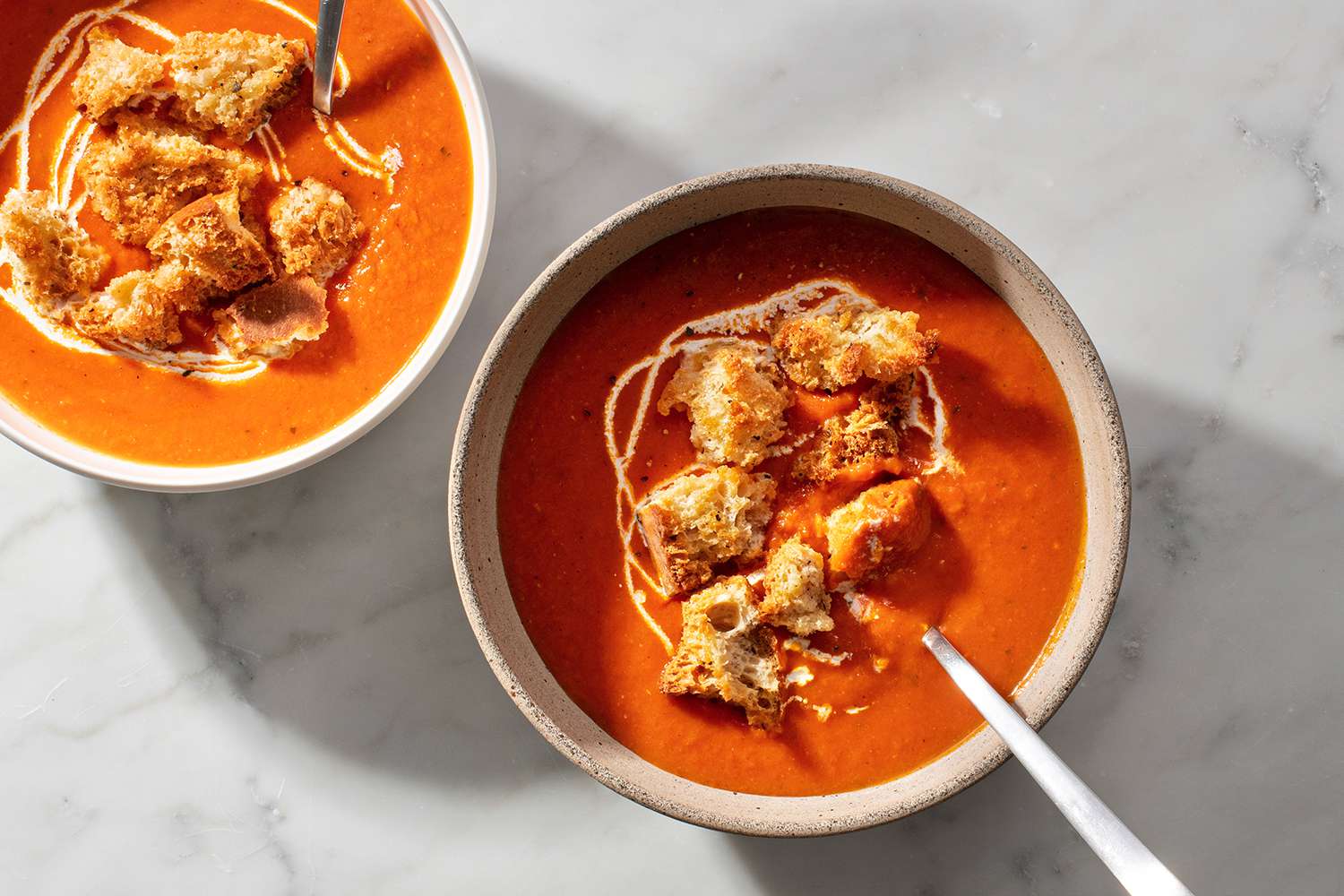Perfect Tomato Soup in bowls, with croutons and a splash of heavy cream on top