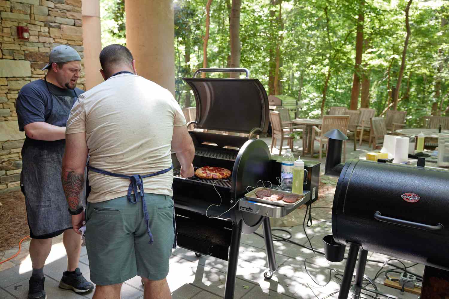 Two people standing in front of the Weber Smokefire EX4 (2nd Gen) Wood Fired Pellet Grill