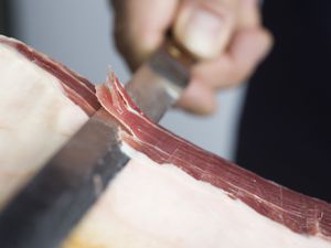 A knife slicing prosciutto