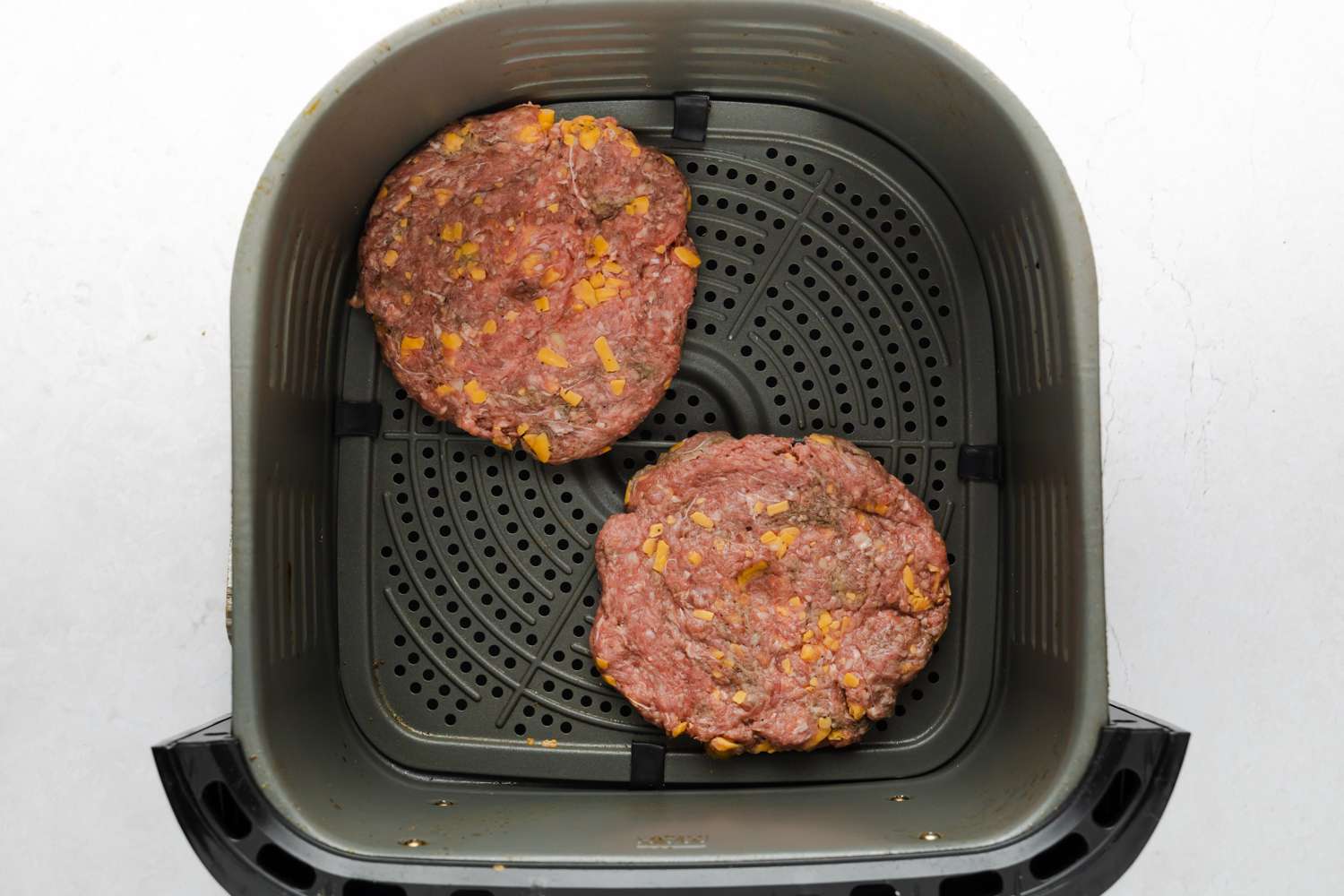 two burger patties in the air fryer