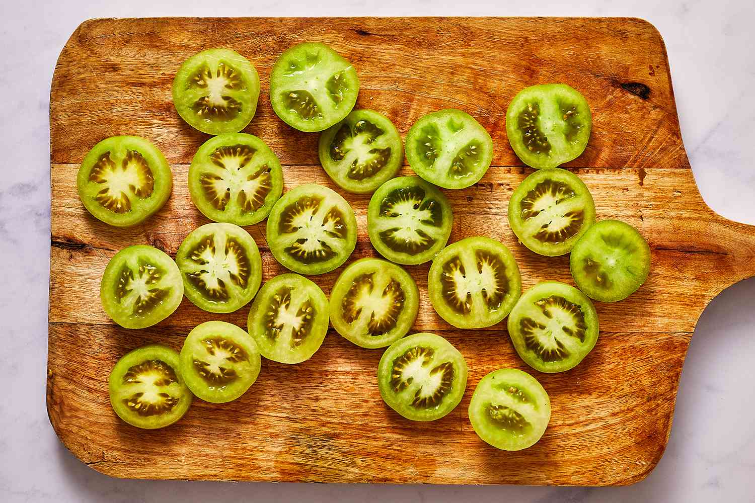 sliced green tomatoes on a wood cutting board