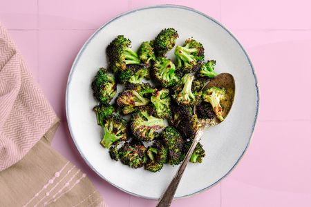 A plate of browned roasted broccoli with a serving spoon