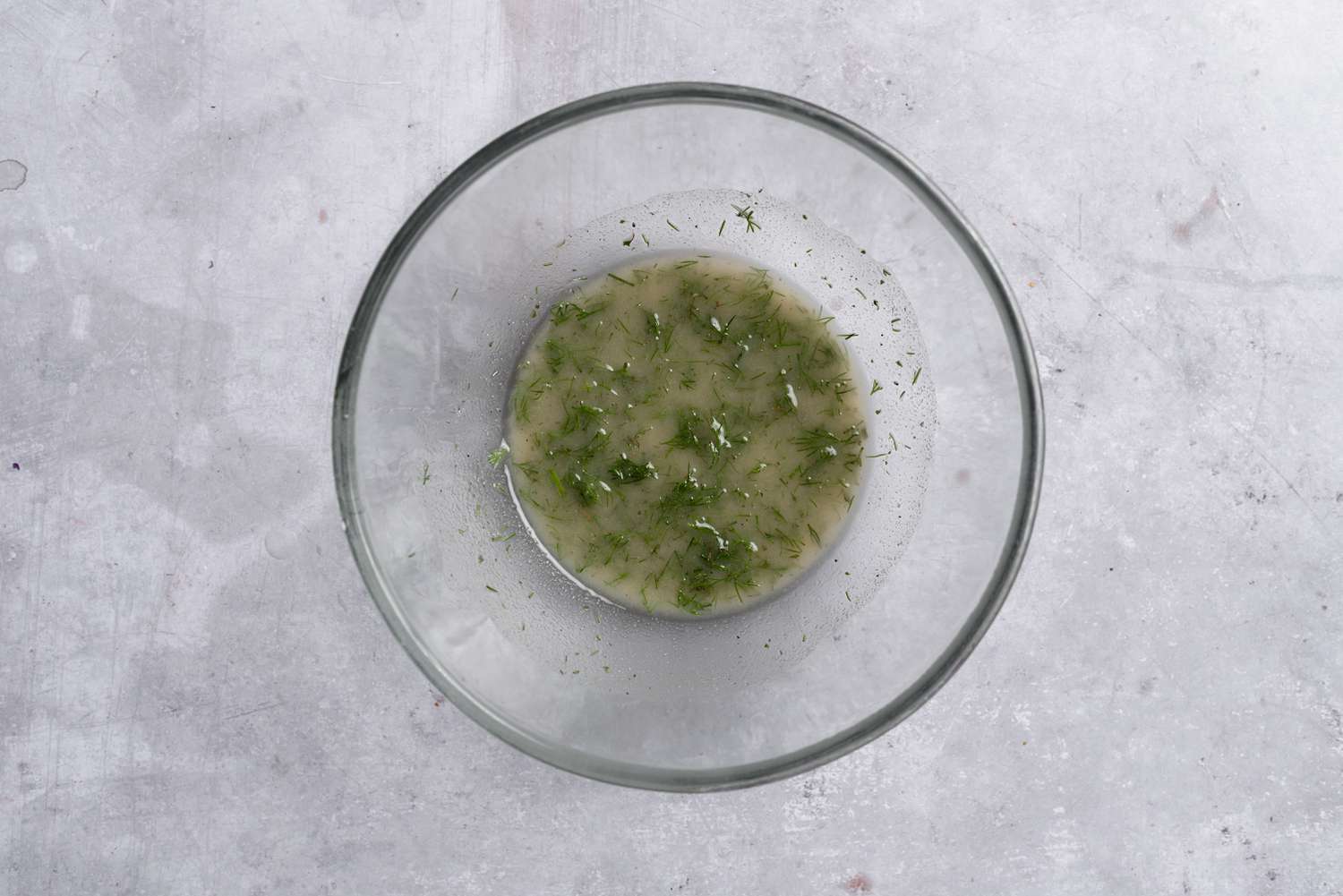 A bowl with vegetable oil, ranch dressing mix, dill, and garlic powder