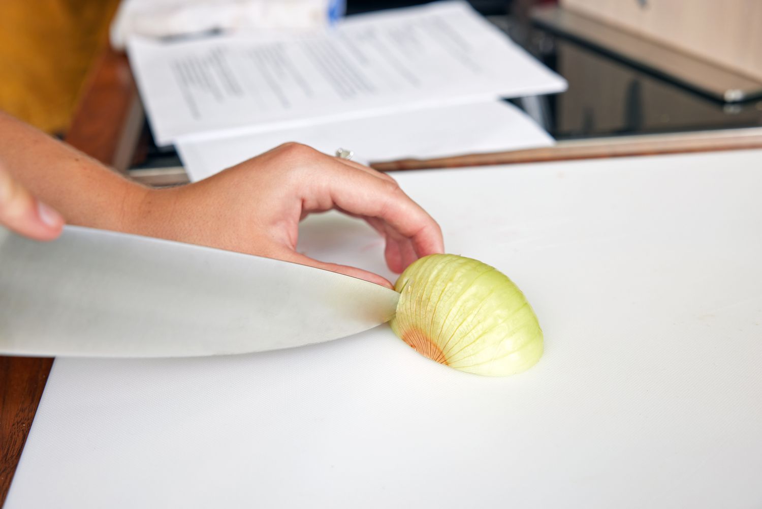 Person slicing an onion with Material The 8-Inch Knife